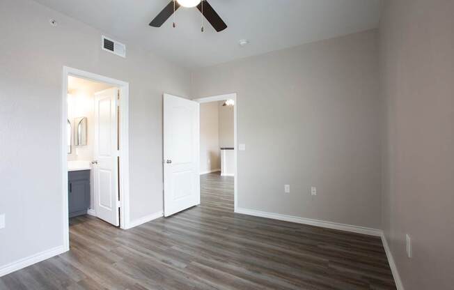 A room with a ceiling fan and wooden flooring.