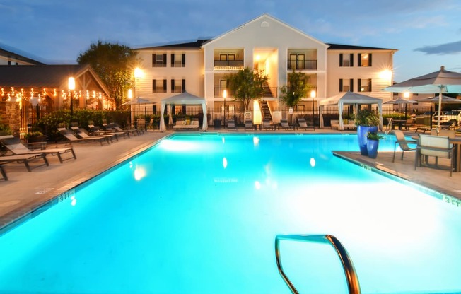 a swimming pool at night with a hotel in the background at Avalon Apartment Homes, Starkville, 39759