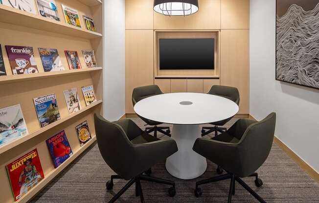 a small meeting room with a white table and four gray chairs