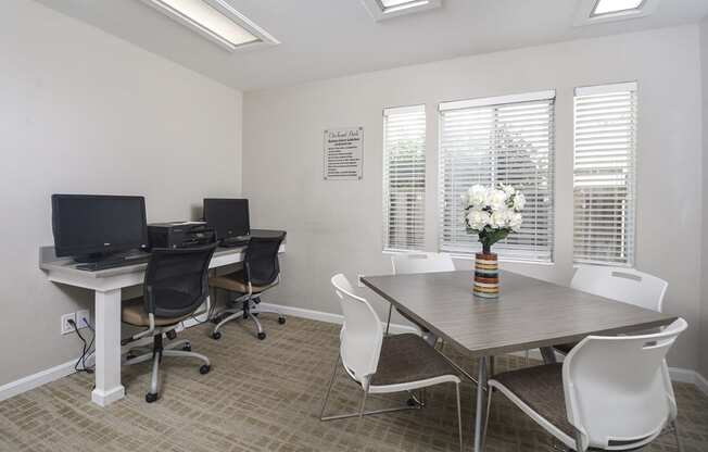 a conference room with three computers and a table and chairs
