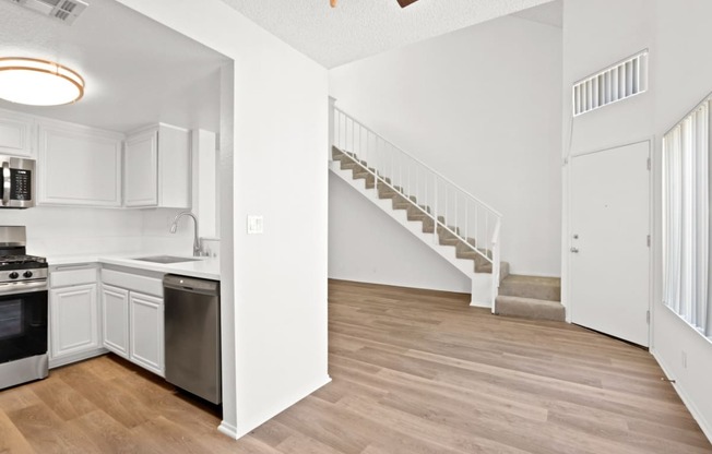 an open kitchen and living room with a staircase in a home