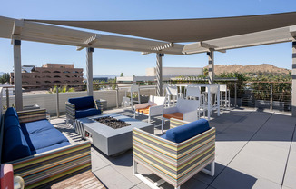 a rooftop patio with couches and chairs and a fire pit