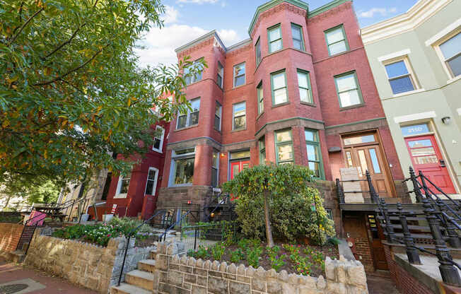 A red brick building with a green tree in front.