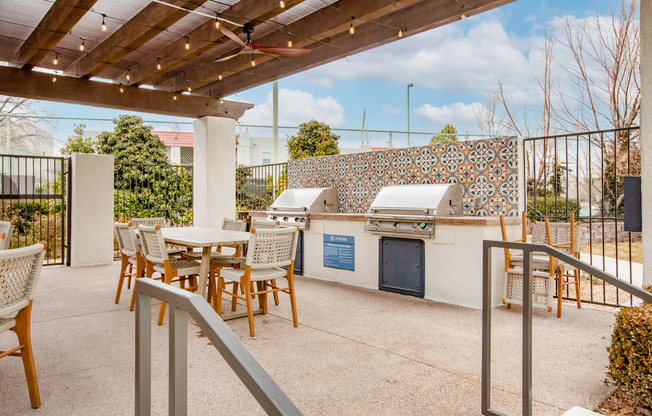 a patio with a grill and tables and chairs