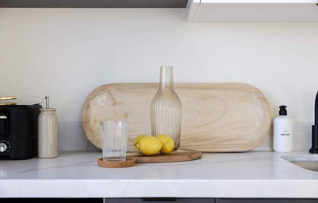 A kitchen counter with a cutting board, a bottle, a glass, and lemons at Skylar At Sunset Apartments, Los Angeles, CA