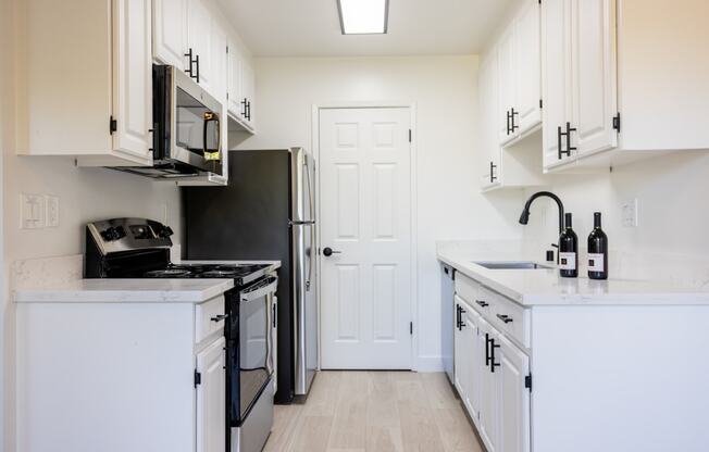 a kitchen with white cabinets and a black stove and refrigerator at Campbell West Apartments, Campbell, 95008