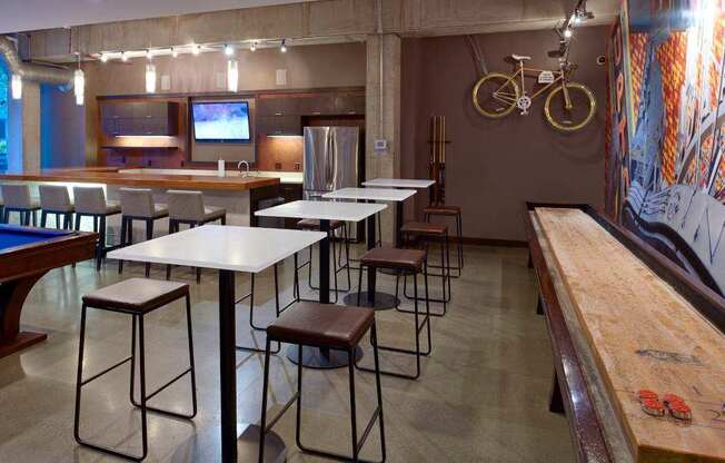 A room with a pool table, bar stools, and a television.