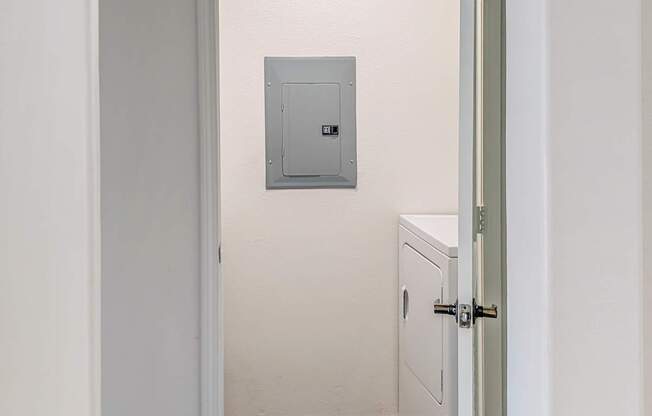A white door with a grey frame is open to a hallway.
