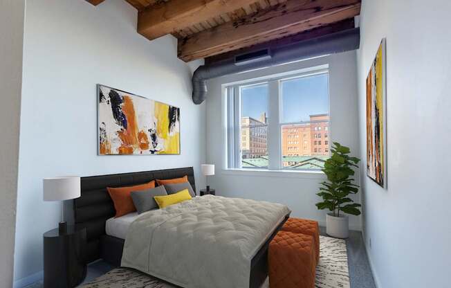 A bedroom with a large bed and a window overlooking a cityscape at Lowertown Commons Apartments, Minnesota, 55101