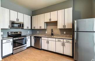 A kitchen with a refrigerator, oven, and microwave.