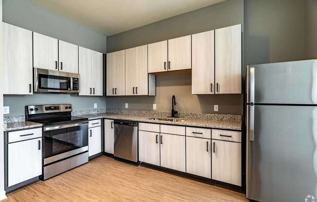 A kitchen with a refrigerator, oven, and microwave.