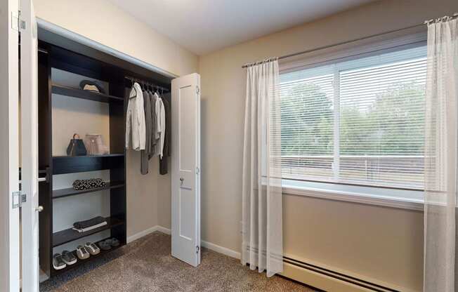 a closet in a bedroom with a window and a closet door