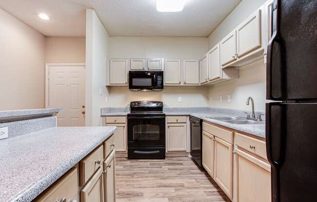 a kitchen with light wood colored cabinets and black appliances