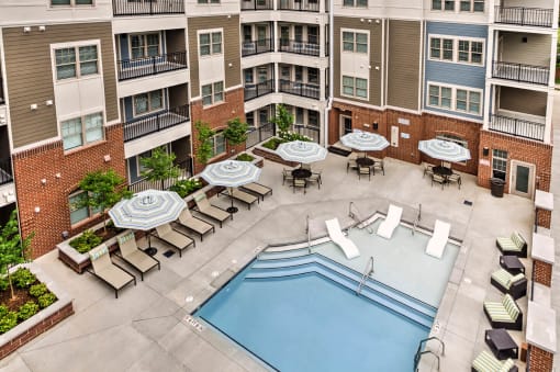 an aerial view of an apartment building with a pool and lounge chairs