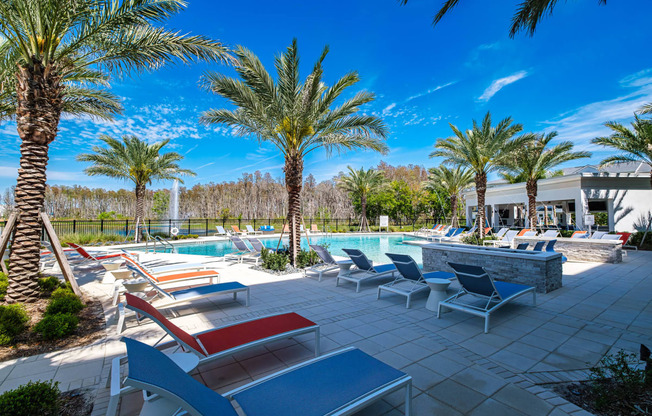 a swimming pool with lounge chairs and palm trees at Altis Grand Suncoast, Land O' Lakes, 34638