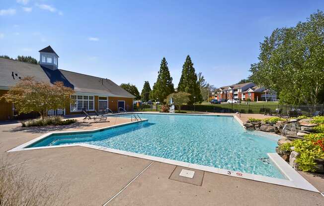 A large outdoor swimming pool surrounded by trees and a building.
