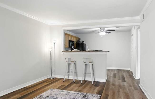 A kitchen with white walls and wooden floors with a bar area.