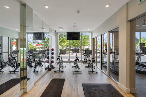 a gym with weights machines and a tv on the wall