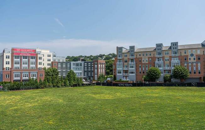 A grassy field in front of apartment buildings.