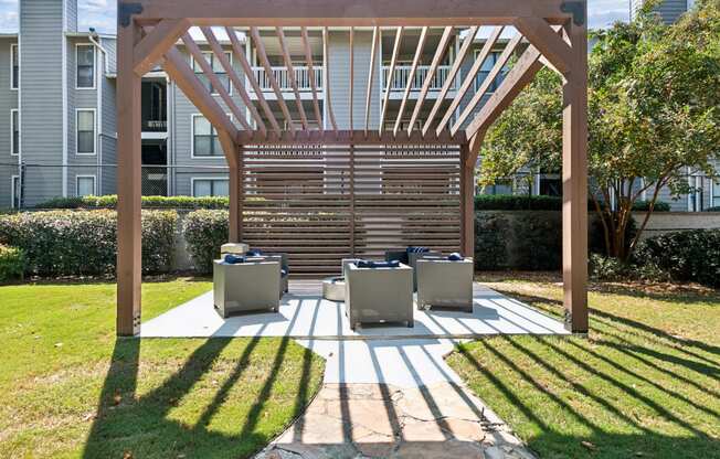 a covered patio with chairs and a wooden pergola