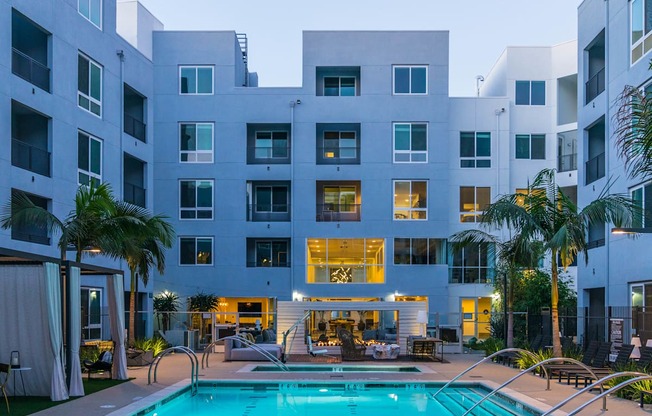 A modern apartment complex with a pool in the foreground.