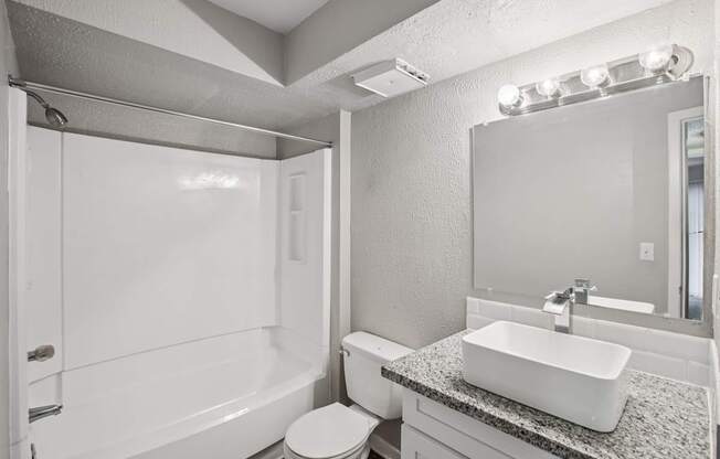 A white bathroom with a toilet, sink, and mirror.
