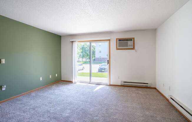 A room with a carpeted floor and a window with a view of the outside. Fargo, ND Stonebridge Apartments