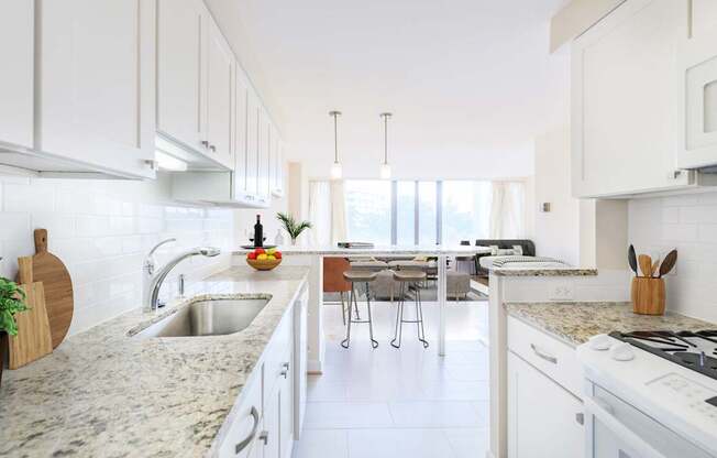 A kitchen with white cabinets and a marble countertop.
