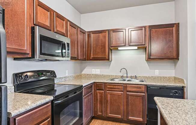 A kitchen with brown cabinets and black appliances.