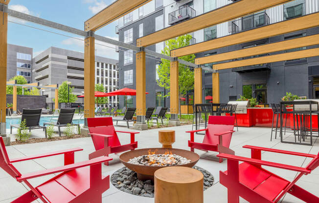 a patio with red chairs and tables and a fire pit