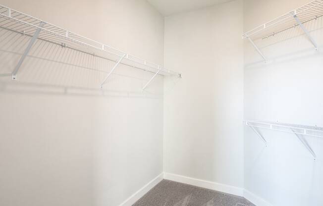 a walk in closet with white walls and shelves and a window at The Bella at Westchester, Midlothian, VA, 23113