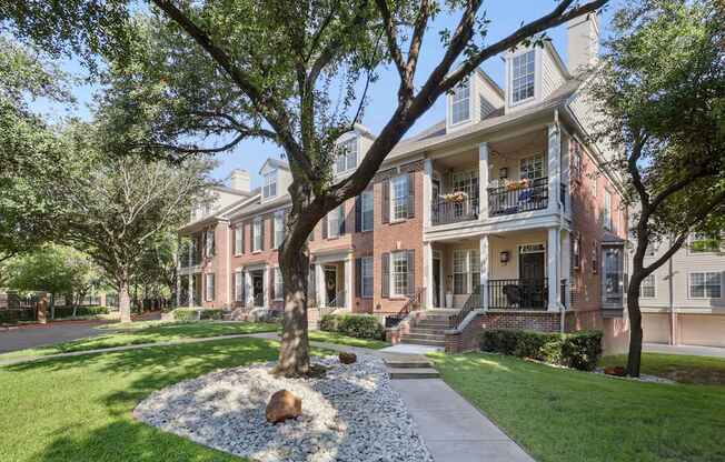 A large tree in front of a red brick house.