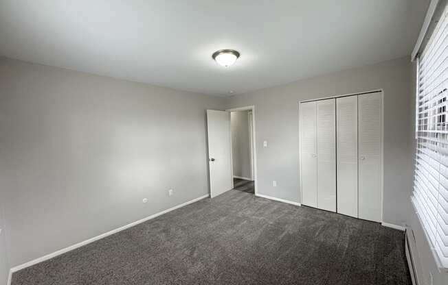 a bedroom with a carpeted floor and a closet