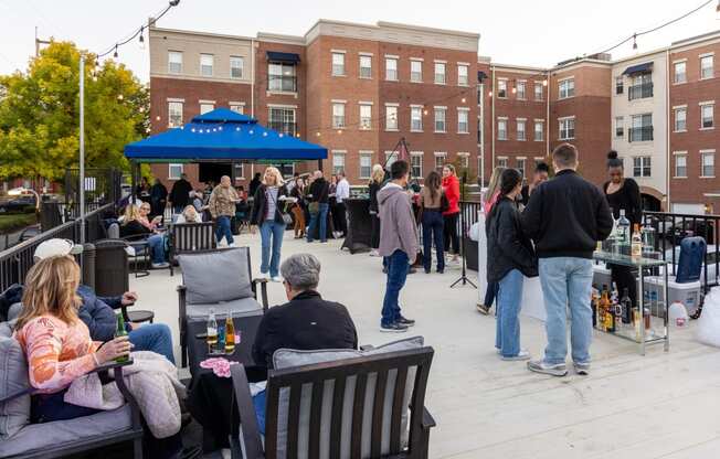 a crowd of people standing and sitting around an outdoor patio