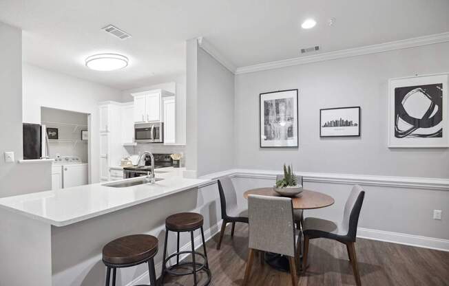 A kitchen with a bar and chairs.