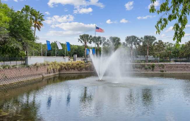 A fountain in the middle of a pond with the American flag in the background.