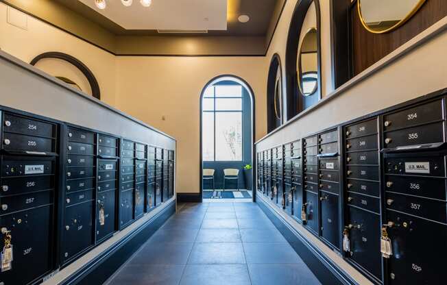 a row of lockers in a hallway with a large window at the end of the hallway