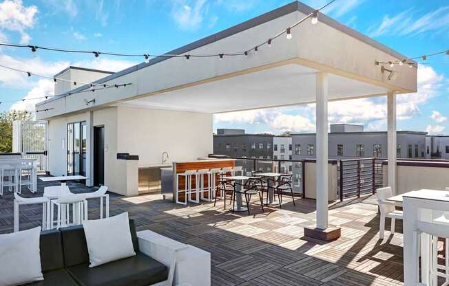 A white patio with a black couch and a table with chairs.