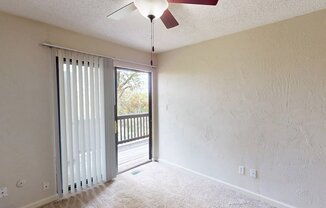 an empty living room with a ceiling fan and a door to a balcony