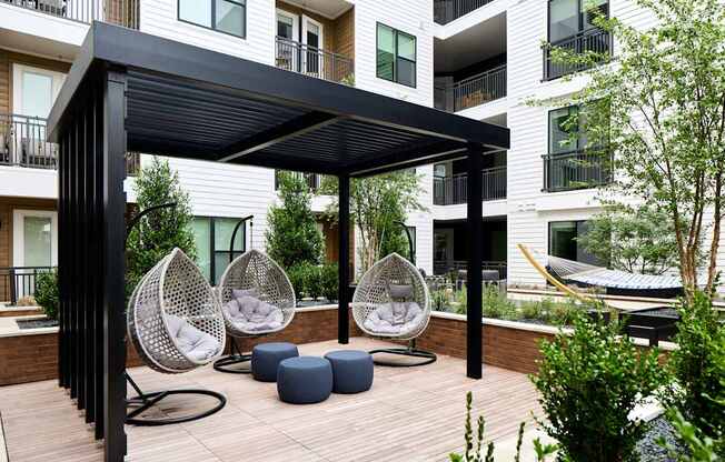 A patio with a black canopy and white wicker chairs.