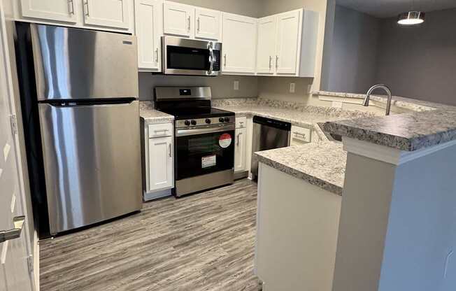 A kitchen with a refrigerator, oven, and microwave.