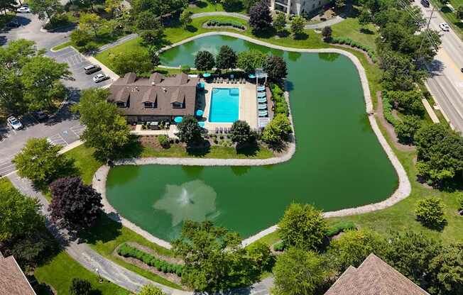 A large house with a pool and a green pond in front.