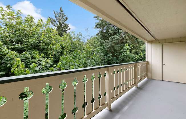 a balcony with trees in the background at Swiss Gables Apartment Homes, Kent, WA