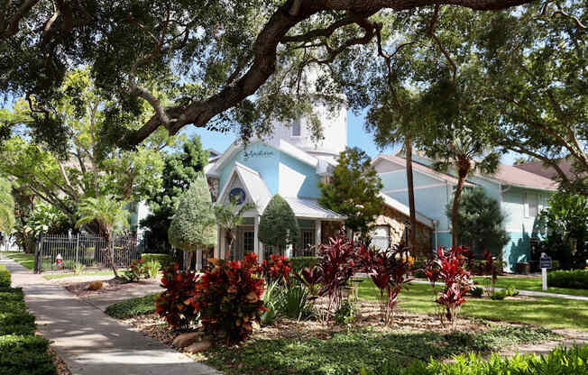 A house with a blue roof is surrounded by greenery.