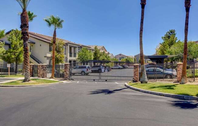 A street view of a gated community with palm trees and houses.