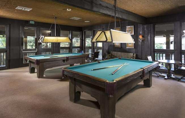 a game room with two pool tables and lamps