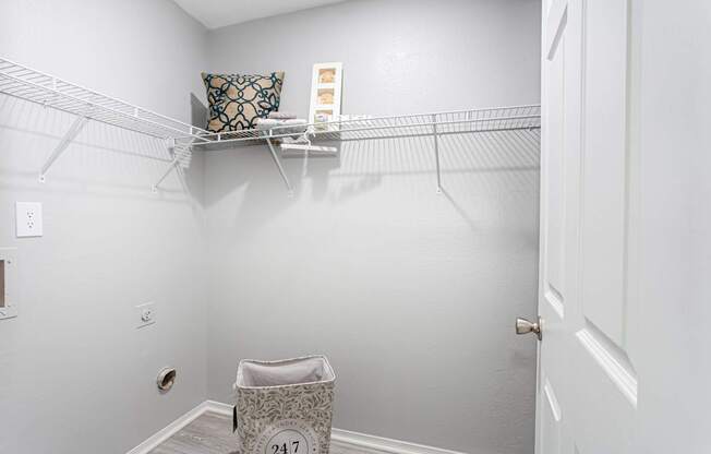 A white closet with a shelf and a laundry basket.