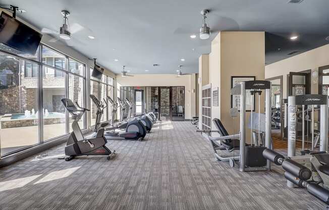 a gym with treadmills and other exercise equipment in a building with large windows