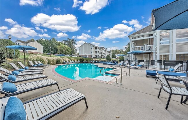 a resort style pool with lounge chairs and umbrellas in front of a building