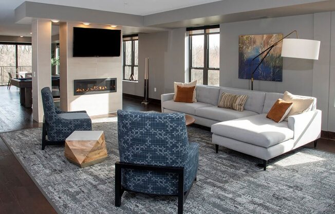 Community space with large sectional couch, fireplace and mounted flatscreen